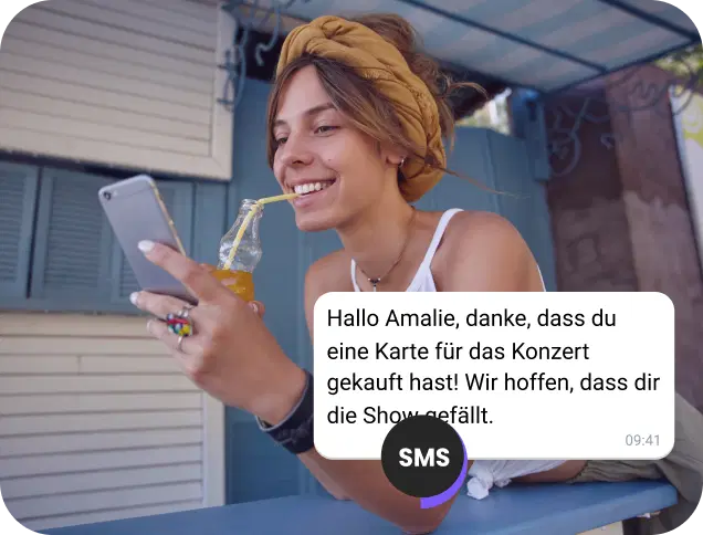 Ein Mädchen genießt einen Saft auf der Straße und liest eine SMS-Bestätigung für ein Konzertticket.