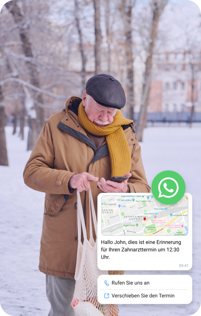 Ein älterer Mann überprüft eine WhatsApp-Nachricht mit Standortinformationen, während er im Schnee steht.